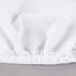 A white fabric crib pad cover with ruffled edges.