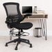 A Flash Furniture black mesh drafting chair with flip up arms and an adjustable foot ring.