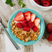 A Tuxton Concentrix Island Blue china bowl filled with granola, strawberries, and raspberries.