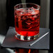 A Libbey Lexington rocks glass with red liquid, ice, and a straw.
