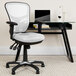 A white Flash Furniture office chair with triple paddle controls next to a black desk.