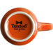 An orange Tuxton mug with a white rim and black text on the front.