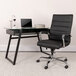 A Flash Furniture black leather office chair next to a glass desk with a laptop on it.
