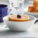 A Tuxton white china bowl filled with orange slices and a blueberry.