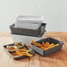 A stack of rectangular gray plastic American Metalcraft serving trays with food in them.