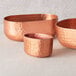An American Metalcraft copper sugar packet holder with a hammered design holding sugar packets.