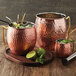 American Metalcraft hammered copper mugs filled with a drink and limes on a counter.