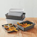 A stack of American Metalcraft rectangular gray plastic serving trays with food on them.