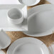 A Tuxton Pacifica bright white embossed china plate with a white bowl on a white surface.
