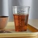 A Solo Ultra Clear PET plastic measuring cup with brown liquid on a tray.