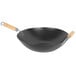 A black wok with wooden handles.