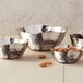 A group of American Metalcraft stainless steel bowls with nuts and almonds in them.
