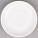 A Tuxton bright white China saucer on a gray surface.