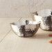 Two American Metalcraft silver snack bowls on a wood surface filled with nuts and almonds.