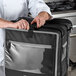 A chef preparing a Vollrath 3-Series delivery backpack bag on a counter.