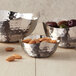 Three American Metalcraft stainless steel snack bowls with a textured surface filled with nuts and olives.