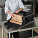 A chef putting pizza boxes into a Vollrath insulated delivery bag.