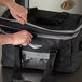 A person opening a black Vollrath food pan carrier bag.