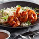 A plate of food with shrimp and rice covered in Frank's RedHot XTRA Hot Cayenne Sauce.