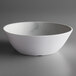 A white Carlisle melamine bowl with a gray rim on a gray surface.