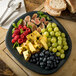 A Carlisle Slate Melamine platter with fruit and bread on a table.