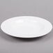 An Arcoroc white porcelain soup plate on a gray background.