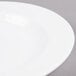 A close-up of an Arcoroc white porcelain soup plate with a white rim.