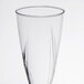 A close-up of a WNA Comet clear plastic champagne glass with a swirl design.