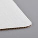A close-up of a white Baker's Mark corrugated cake pad.