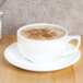 A white CAC porcelain cappuccino cup on a saucer with foamy brown coffee.