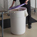 A man using a purple lid to open a large white ingredient storage bin.