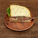 A sandwich with meat and vegetables on a checkered bamboo melamine plate.