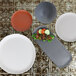 A rectangular dark gray speckled melamine platter on a table with a variety of plates and bowls.