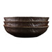 An oval wood grain melamine serving bowl stacked with other bowls.