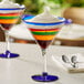 An Acopa martini glass with colorful layers of a drink and dessert.