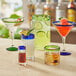A group of Acopa martini glasses with different colored drinks. One has a green rim and base.