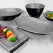 A group of Elite Global Solutions Basalt oval coal melamine serving bowls with food in them.
