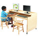 A boy sitting at a Whitney Brothers adjustable height wood desk with a computer monitor and keyboard.