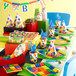 A table set with Creative Converting Block Party paper cups filled with candy on a table with colorful party decorations.