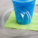 A clear plastic squat dome lid on a plastic cup with a blue drink inside.
