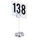 An American Metalcraft chrome swirl base card holder with a white card and black numbers on a table.