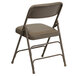 A beige metal folding chair with a padded vinyl seat.
