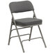 A gray metal folding chair with a padded fabric seat.