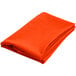 An orange Intedge round cloth table cover folded up on a white background.