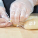 A person wearing plastic gloves putting bread in a plastic bag.