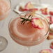 A glass of pink Finest Call Frose mix with a rosemary garnish.