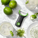 An OXO "Y" peeler next to a lime and a glass of liquid.