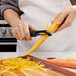 A person using an OXO straight vegetable peeler to peel a carrot.