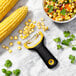 An OXO yellow and black "Y" corn peeler with corn in a bowl.