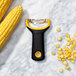 An OXO yellow and black "Y" corn peeler with a few kernels on it.